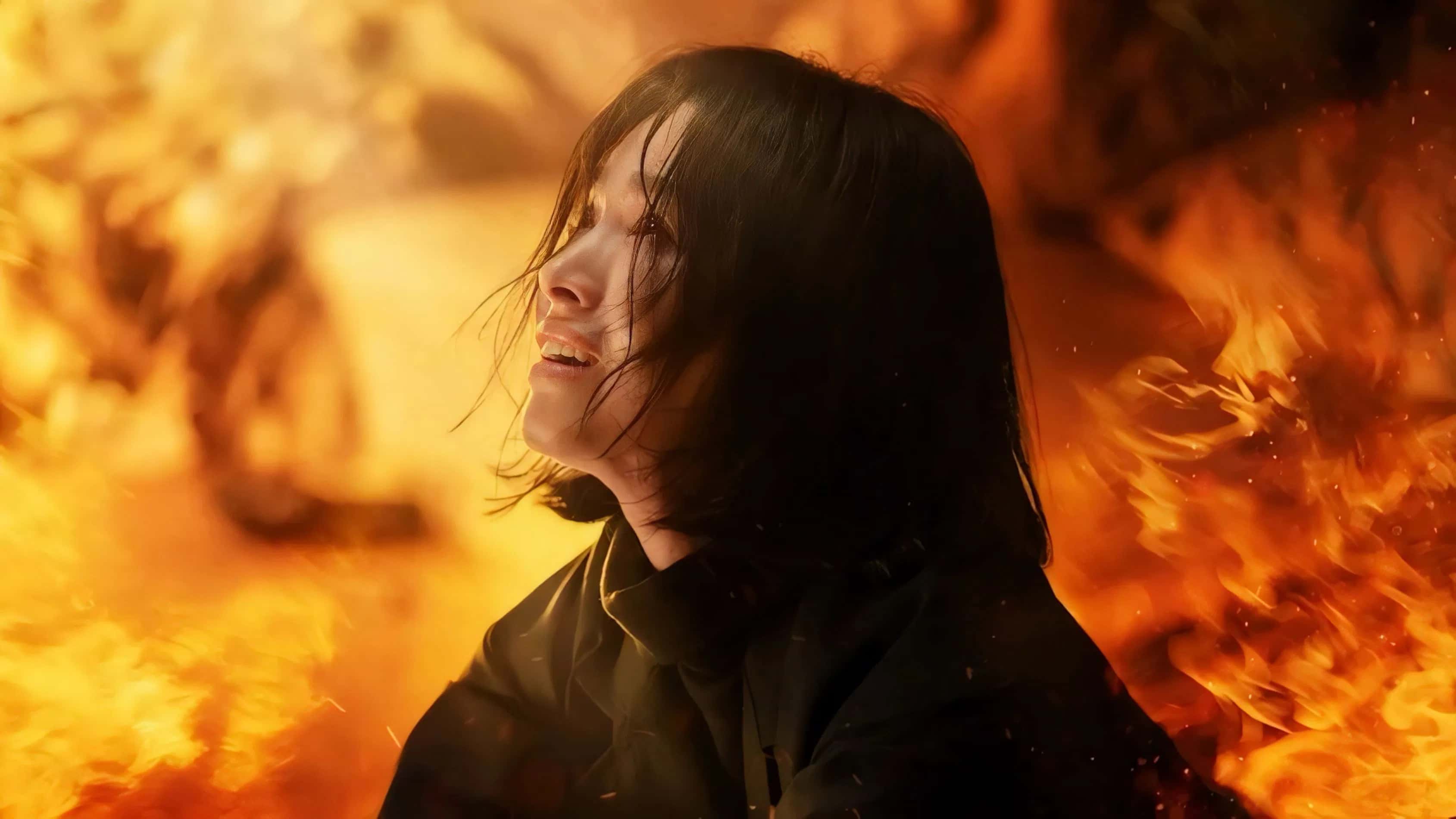 Moon Dong-eun looks upward with flames surrounding her in the background.